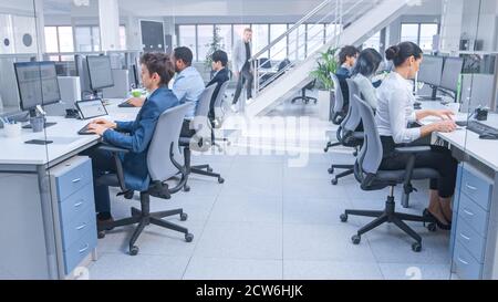Diverse Team of Business Managers and Specialists Work on Desktop Computers with Two Rows of Tables Side by Side. Young and Motivated Business people Stock Photo