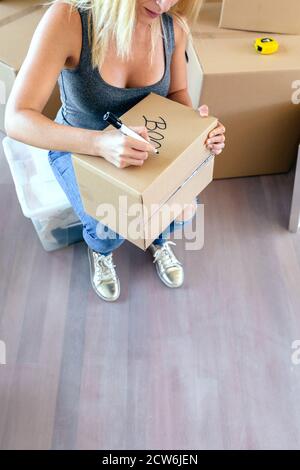 Sitting woman labeling moving boxes Stock Photo