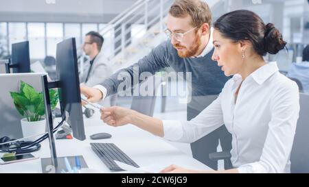Beautiful Businesswoman Uses Desktop Computer, Consults Her Project Manager about Documents with Graphs and Statistics. In the Background Big Stock Photo