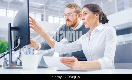 Beautiful Businesswoman Uses Desktop Computer, Consults Her Project Manager about Documents with Graphs and Statistics. In the Background Big Stock Photo