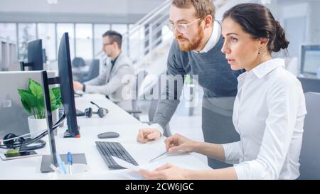 Beautiful Businesswoman Uses Desktop Computer, Consults Her Project Manager about Documents with Graphs and Statistics. In the Background Big Stock Photo