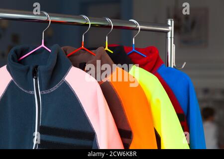 Colorful fleece jackets are hanging on hangers close-up Stock Photo