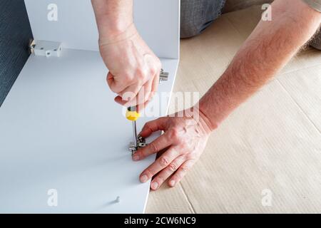 Joiner collects furniture using hand tools screwdriver. Furniture assembly. Moving, home improvement, furniture repair and renovation. Carpenter Stock Photo