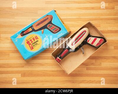 Tin toy gun in a cardboard box with vintage design packaging on wooden table Stock Photo