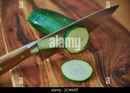 Wooden cutting board with fresh vegetables and a chef's knife. Chopping vegetables on a wooden cutting board. Stock Photo