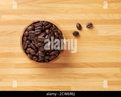 A bowl full of coffee beans with three coffee beans outside Stock Photo