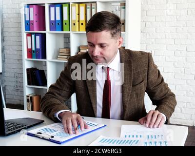 Young businessman checks financial statements and works with business graphs and results. Stock Photo