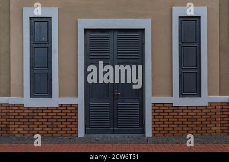 Wall with wooden doors and closed windows. Stock Photo