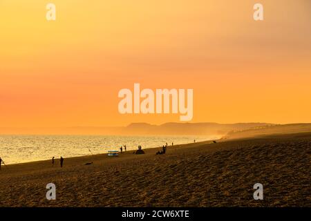 Fishermen on the beach at sunset at West Bexington, a village in south-west Dorset, England, sited behind Chesil Beach near Bridport Stock Photo
