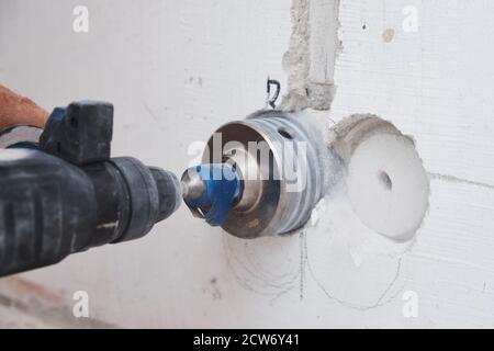 Builder with hummer drill perforator drills hole in the wall Stock Photo