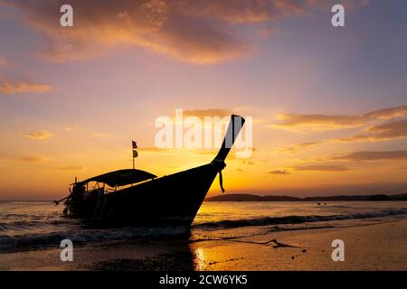 Traditional long-tail boat on the beach in Thailand at sunset Stock Photo