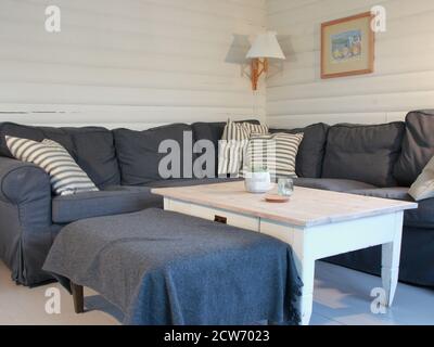 A cosy grey large corner couch with a white table. The colors are grey and white. Stock Photo