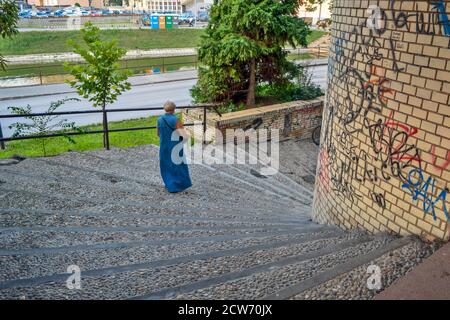 Zrenjanin, Serbia, August 20, 2016. A woman in a long denim dress coming down the stairs. Stock Photo