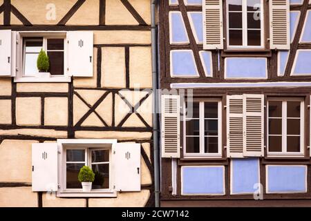 Old fashioned half timbered facades, cute small windows with shutters. Rustic elevation. French traditional architecture,close-up. Alsace, Colmar Stock Photo