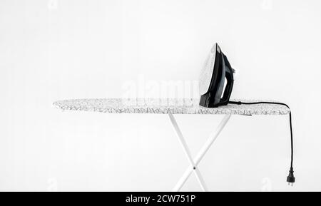 iron on ironing board against white wall background. High quality photoiron on ironing board against white wall background. dirty laundry before ironing after washing Stock Photo