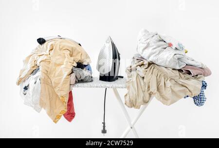 iron on ironing board against white wall background. High quality photoiron on ironing board against white wall background. dirty laundry before ironing after washing Stock Photo