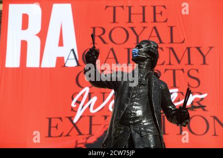 NOTE TO EDITORS. FOR USE IN RELATION TO THE EXHIBITION ONLY. The statue of Sir Joshua Reynolds wearing a mask outside the Royal Academy of Arts in London. The 252nd Summer Exhibition was postponed because of the coronavirus pandemic and will take place in the autumn for the first time. Stock Photo