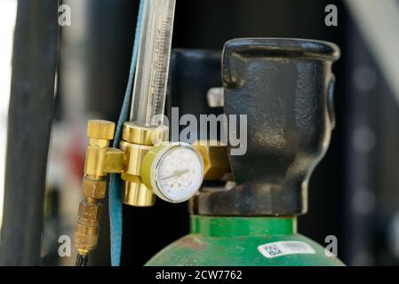 Welding gas cylinder with pressure gauge regulators manometers. Close up view of argon storage tank for pipe welding industry
