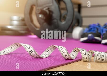 Fitness tools dumbbells yoga mat and shoes on a wooden floor in natural light. Healthy living concept. Stock Photo