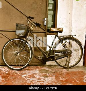 Vintage bicycle parked against a wooden door. Stock Photo