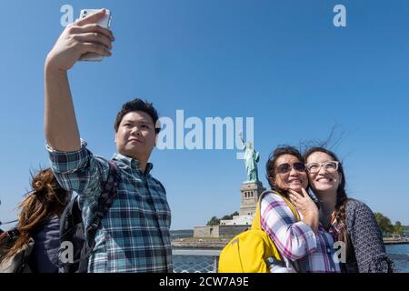 Tourists on the Statue of Liberty Ferry Taking Photos and Selfies, NYC, USA Stock Photo