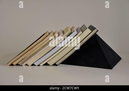 Books on shelf with blue felt pyramid support on white background side view Stock Photo