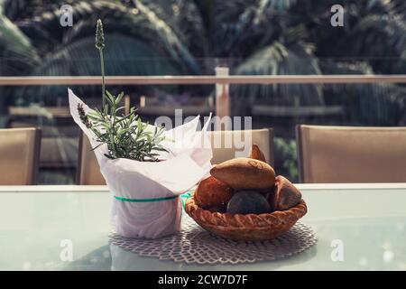 Lavender in a pot covered with a white paper and stone bowl decorations on the table on balcony with tropical rainforest on background Stock Photo