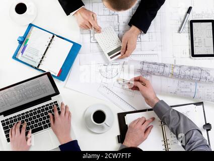 People reviewing blueprints at desk Stock Photo