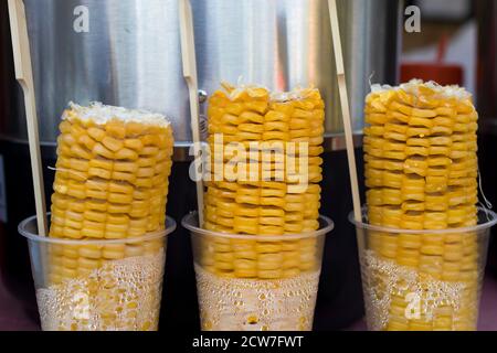 Three cobs of ripe boiled corn for sale in plastic cups in street cafe Stock Photo