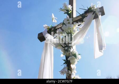 White drape and white lilies (symbols of the Resurrection) over a cross on Easter morning at a church in Virginia, USA Stock Photo