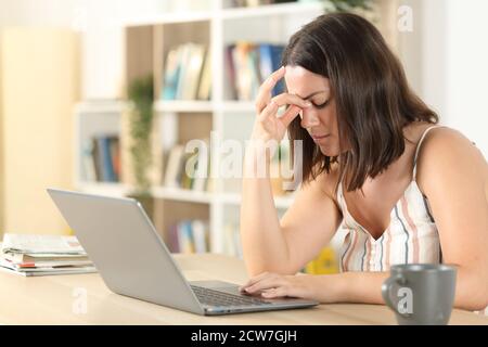 Tired woman suffering eyestrain with a laptop on a desk at home Stock Photo