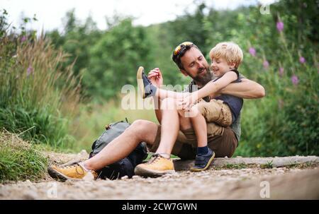 Father with small son hiking outdoors in summer nature, resting. Stock Photo