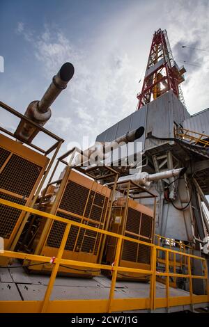 Zhaik-Munai oil deposit, Kazakhstan. Diesel engine station and generators of electricity. Mobile power plant. Oil tower rig on background. Stock Photo