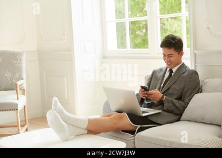 young asian business man wearing suit and shorts working from home texting using cellphone Stock Photo