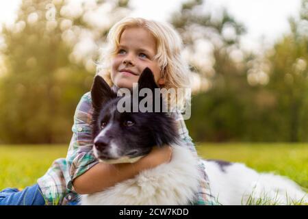 Little boy playing with his dog outdoors in the park Stock Photo