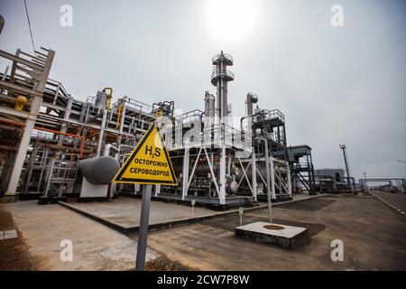 Zhaik-Munai oil deposit, Kazakhstan. Oil refinery & gas processing plant. Distillation tower, pipes & pipelines. Sulphur dioxide (sulfur dioxide) sign. Stock Photo