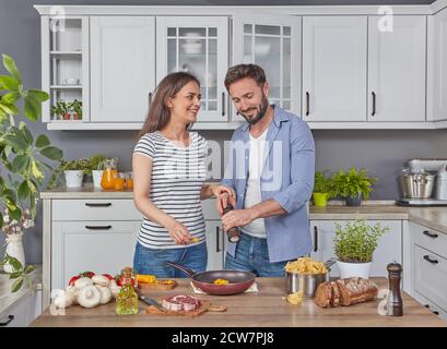 Young cheerful couple cooking together in the kitchen Stock Photo