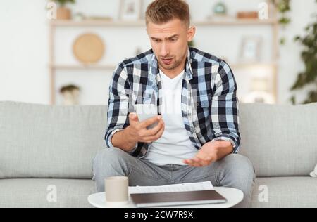 Sad adult man using smart phone at home Stock Photo
