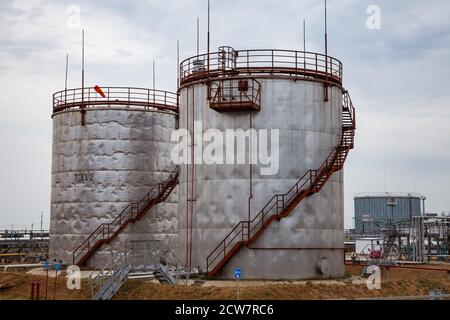Zhaik-Munai oil deposit, Kazakhstan. Oil refinery and gas processing plant in desert. Grey steel or metal storage tanks. Cloudy sky background. Stock Photo