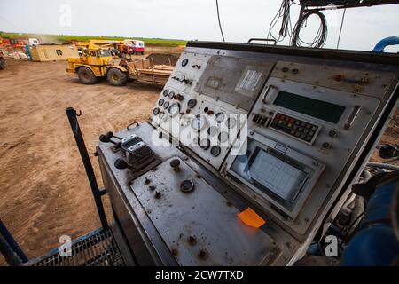Zhaik-Munai oil deposit, Kazakhstan. Drilling rig mud pump control panel close-up. Yellow tractor on background blurred. Stock Photo