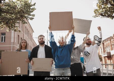 Freedom. Group of activists giving slogans in a rally. Caucasian men and women marching together in a protest in the city. Look angry, hopeful, confident. Blank banners for your design or ad. Stock Photo