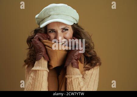 Hello september. smiling elegant 40 years old housewife in scarf with leather gloves looking at copy space isolated on beige background. Stock Photo