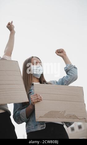 Faith. Group of activists giving slogans in a rally. Caucasian men and women marching together in a protest in the city. Look angry, hopeful, confident. Blank banners for your design or ad. Stock Photo