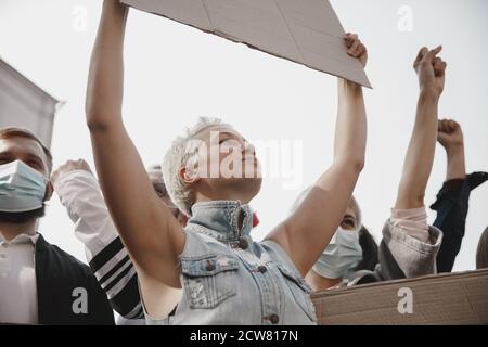 Freedom. Group of activists giving slogans in a rally. Caucasian men and women marching together in a protest in the city. Look angry, hopeful, confident. Blank banners for your design or ad. Stock Photo