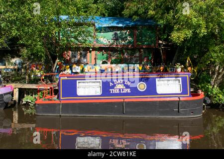 A Day in the Life House boat moored on the Rochdale Canal in front of Mayroyd Moorings building, Hebden Bridge, Yorkshire, UK Stock Photo