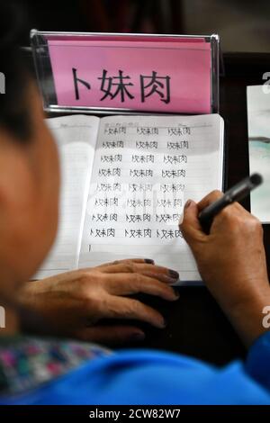 (200928) -- RONGSHUI, Sept. 28, 2020 (Xinhua) -- Miao villager Bu Meirou practices writing her name in Chinese characters during a Mandarin training program in Wuying Village, which lies on the border between south China's Guangxi Zhuang Autonomous Region and southwest China's Guizhou Province, on Sept. 11, 2020. Located deep in the mountains straddling the border between Guangxi Zhuang Autonomous Region and Guizhou Province, Wuying is a remote village inhabited by the Miao ethnic group where women over 40 have hardly ever attended any school. In their childhood, they were occupied with herdi Stock Photo