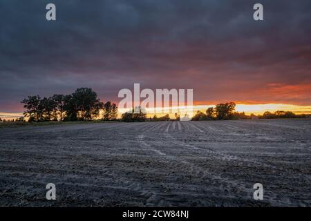 Ploughed field and dark clouds during sunset Stock Photo