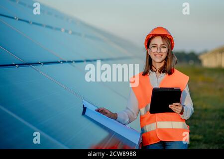 Inspector Engineer Woman Holding Digital Tablet Working in Solar Panels Power Farm, Photovoltaic Cell Park, Green Energy Concept Stock Photo