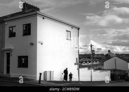 A young boy walking with his father to the Madrasah at the Masjid E Tauheed Mosque Bolt Street which lay within the Shear Brow and Corporation Park ward of Blackburn 2020. The area alongside a number of other areas in the North West and West Yorkhire have been place under additional government restriction in order to suppress the incidence and transmission  of covid 19. The Mosque reopend to its community on the 1st Spetember, 2020, under government covid 19 guidlines. During the Lockdown members of the mosque organised for food parcels to be delivered  to all communities in need within the Bl Stock Photo