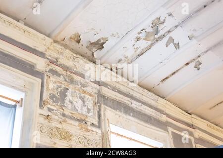 Old room with window peeling plaster in the corners, walls and ceiling in need of repair Stock Photo